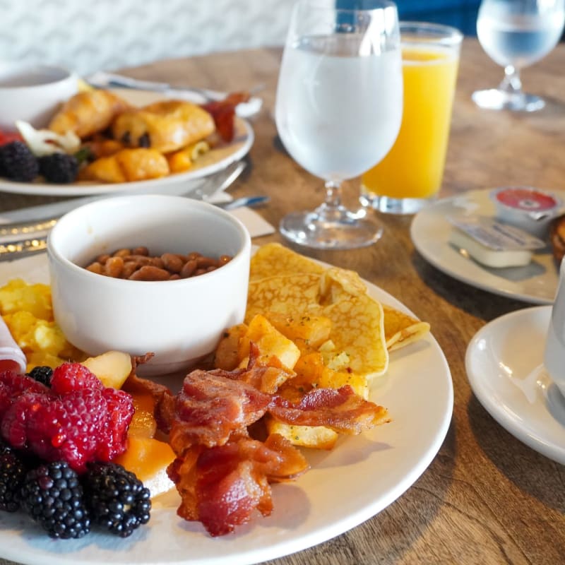 Deux assiettes déjeuner remplies de fruits, bacon et patates. 