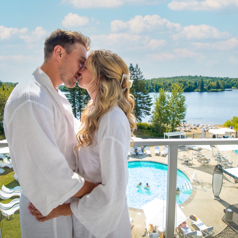 Couple s'embrassant sur un balcon avec la vue sur le lac et le spa - Estérel Resort