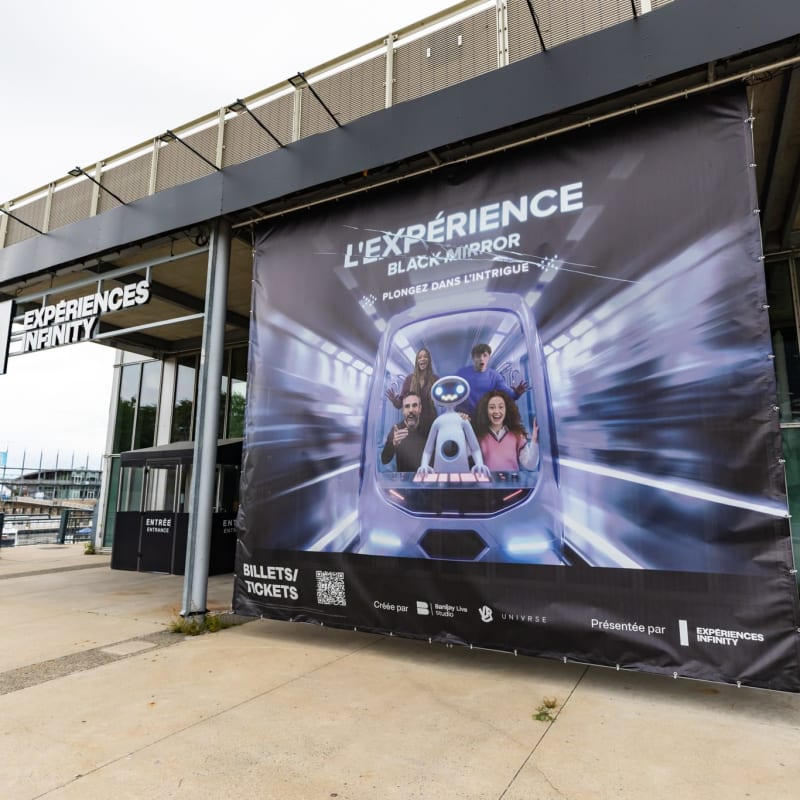 Extérieur du bâtiment d'Expériences Infinity accueillant l'Expérience Black Mirror, avec une grande affiche à l'extérieur.
