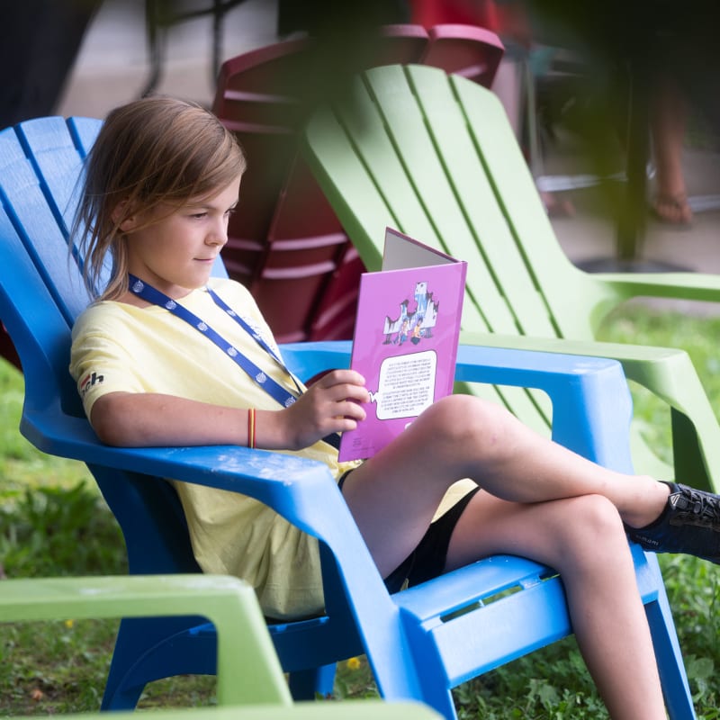 Garçon assis sur une chaise lisant une BD