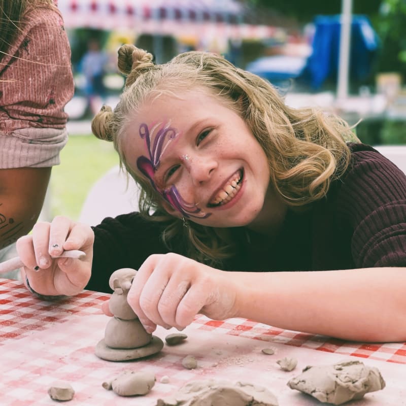 Jeune fille souriante sculptant à l'argile. 