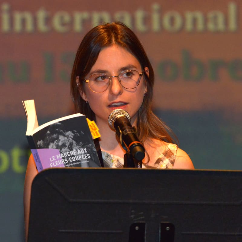 Young girl reading in front of an audiece at a conference at the international poetry Festival in Trois-Rivières.