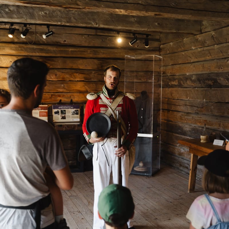 A soldier in uniform standing in front of a family in an old wooden building.