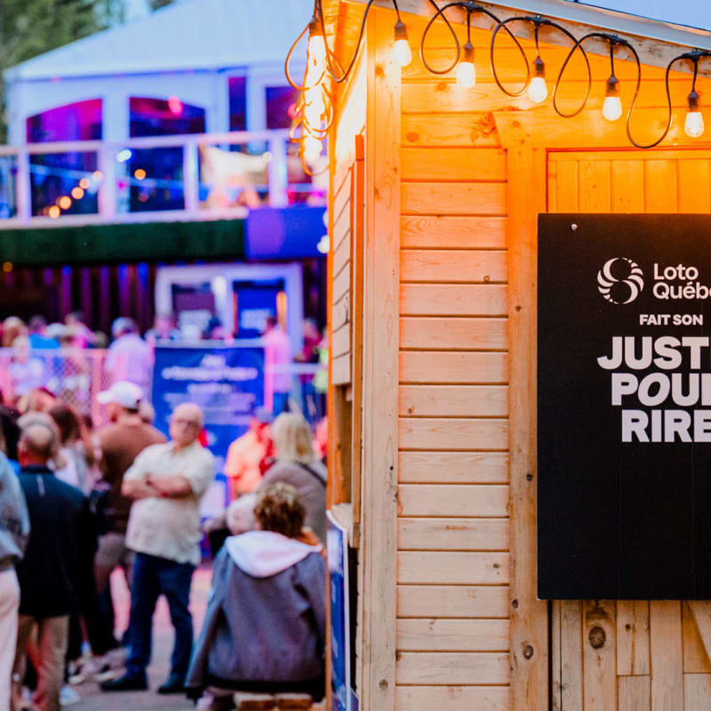 A crowd gathers outside in the evening at the Loto-Québec “Just for Laughs” event.