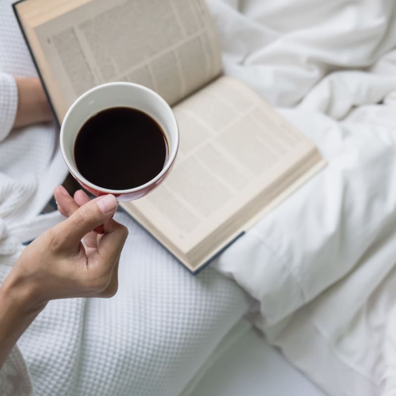 Woman lying in bed with a cup of coffee.