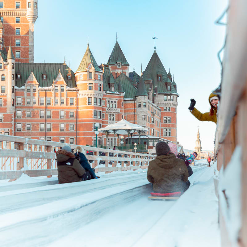 Two couples on sleds with the Château Frontenac in the background.