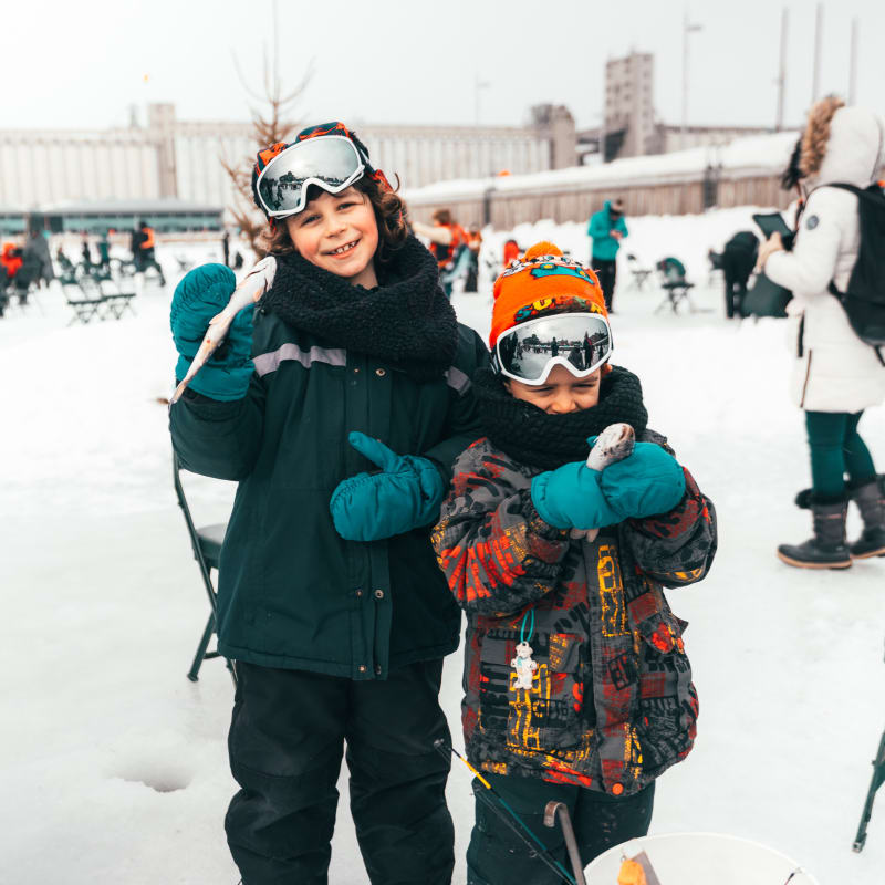 Two children ice fishing at Village Nordik.