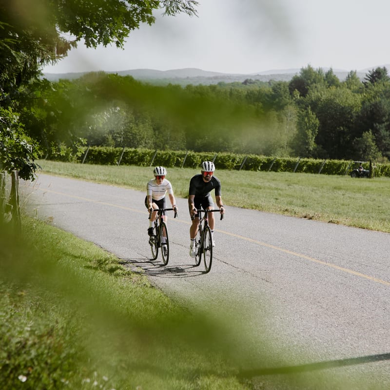 Two people on bicycles on a paved road.
