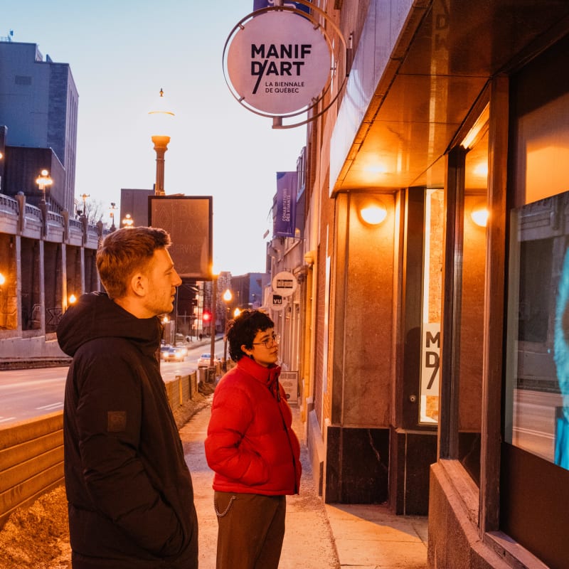 Two people looking at a work of art in front of a display window.