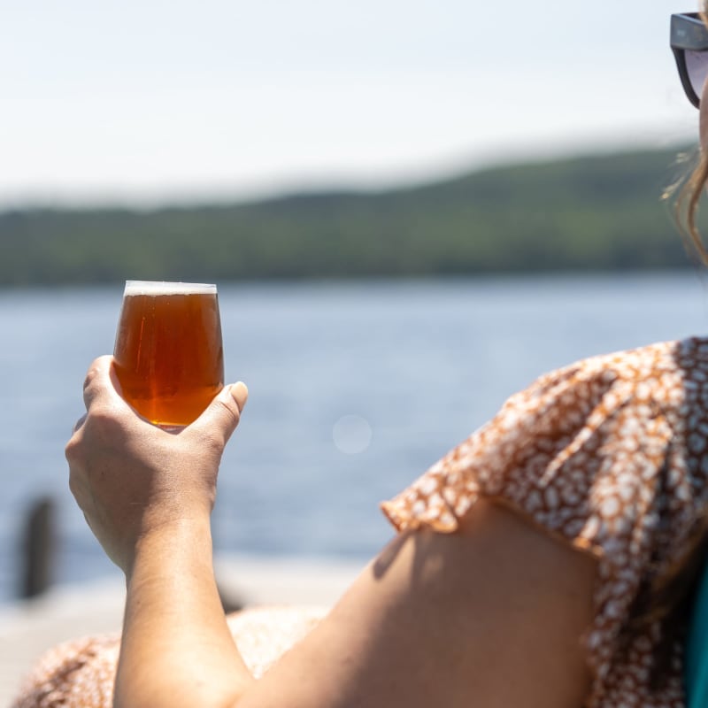 Dame avec bière sur le bord du lac
