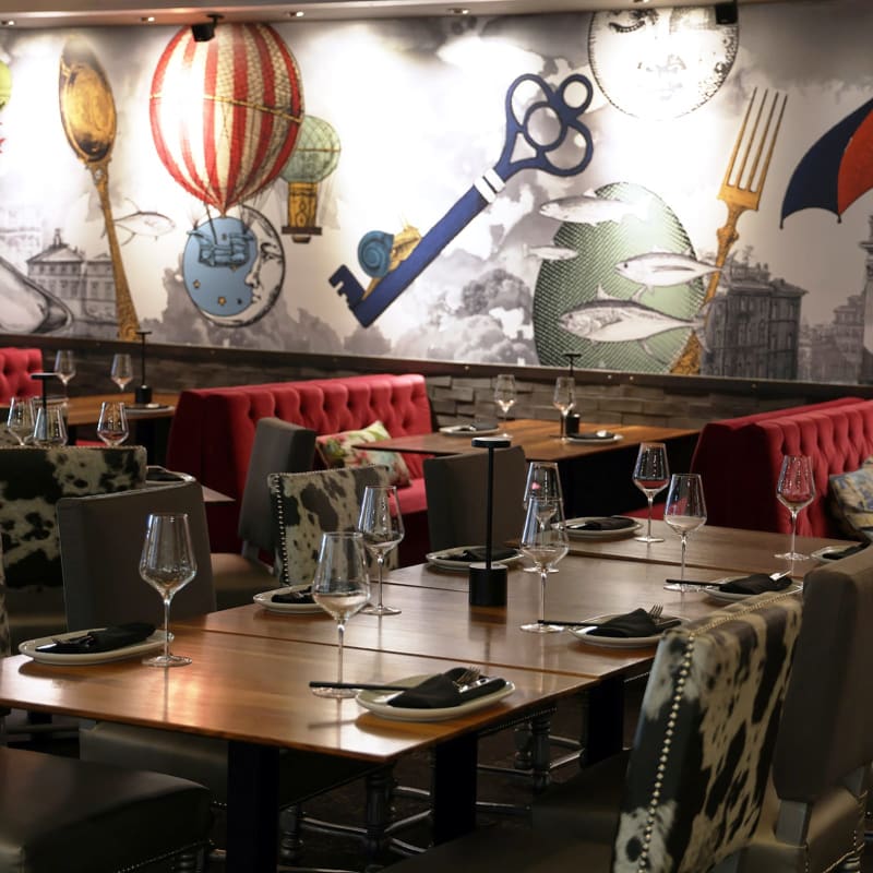 Tables à l'intérieur du restaurant Le M Steak Moderne; le décor est accentué d'éléments rouges.