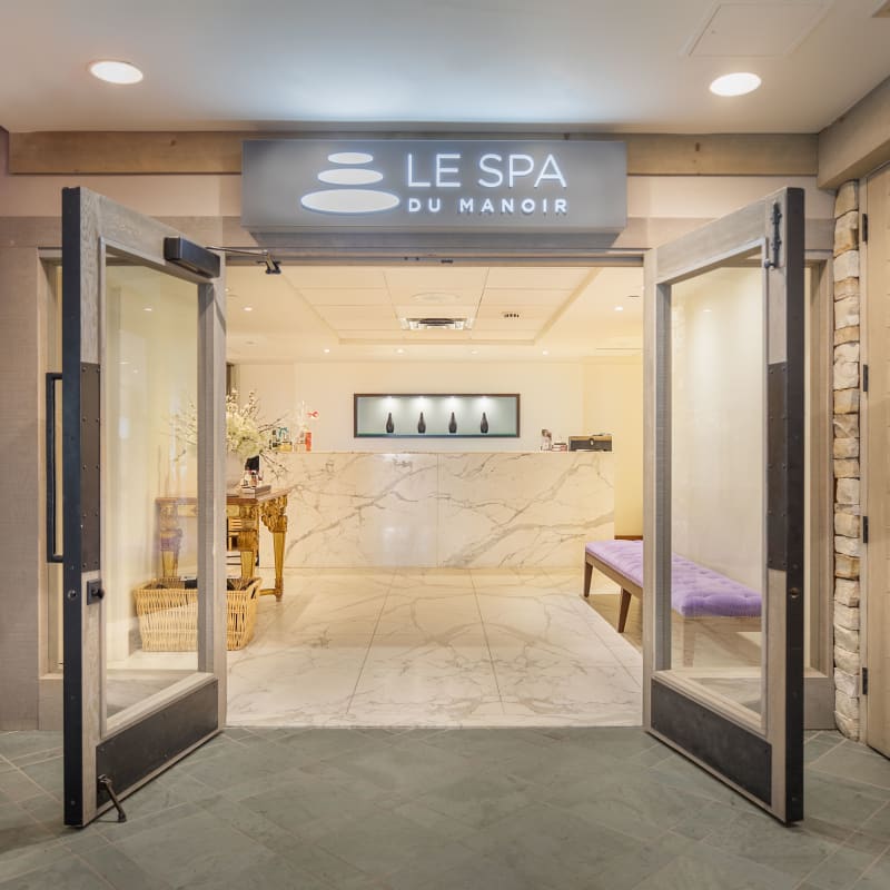 Entrée du Spa du Manoir, avec deux portes vitrées grandes ouvertes sur une pièce lumineuse. 