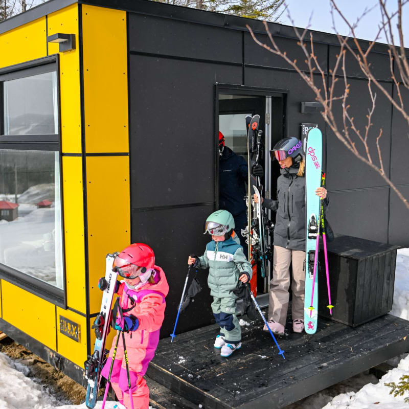 Family outside a Coolbox accommodation at Mont Grand-Fonds.