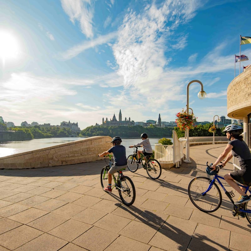 Parent et deux enfants en vélo à l'extérieur du Musée canadien de l'histoire