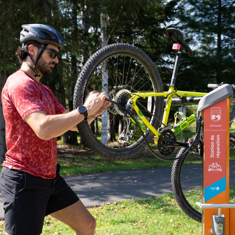 Cyclist fixing his bike on the P'tit train du Nord linear park
