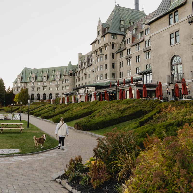 Woman with a dog in front of the Fairmont Manoir Richelieu