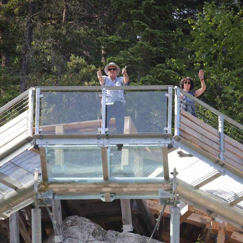 Two visitors on the glass floor at Parc le Trou de la Fée