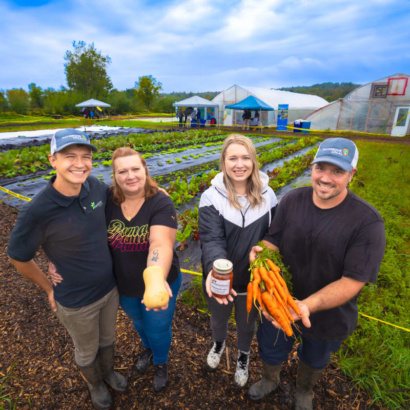 Deux couples dans un champ avec des carottes et produits de la ferme.