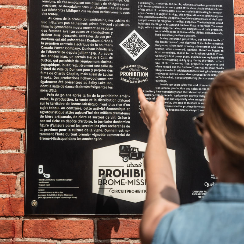 Woman reading a panel on the Prohibition Heritage Trail in Brome-Missisquoi.