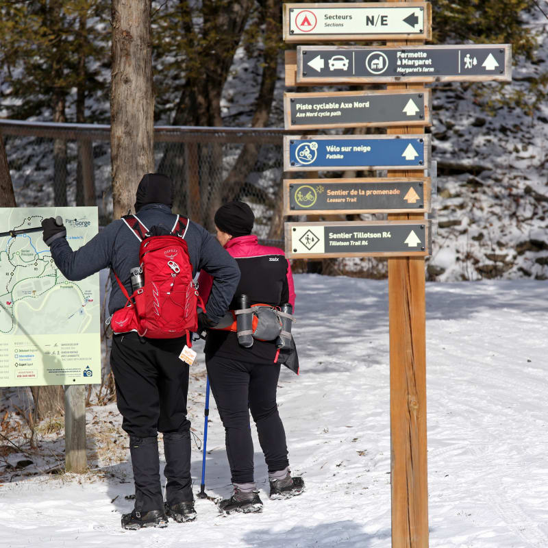 A man and a woman hiking in the winter at the Coaticook Gorge Park.