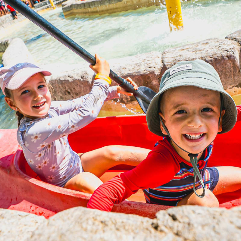 Two young children in a small kayak on a calm water circuit at the Super Aqua Club