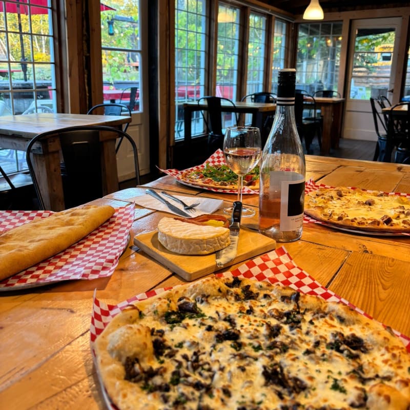 Pizza au jardin - Table en bois sur laquelle sont posées des pizzas et un plateau de fromages.