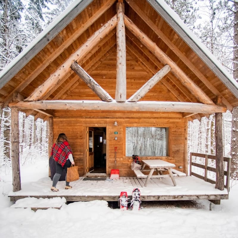 Front of a wooden cabin in winter at Huttopia - Les Deux Lacs