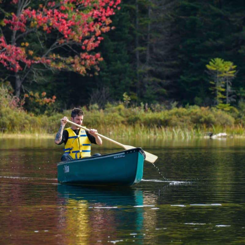 Homme en canot sur un lac à l'automne.
