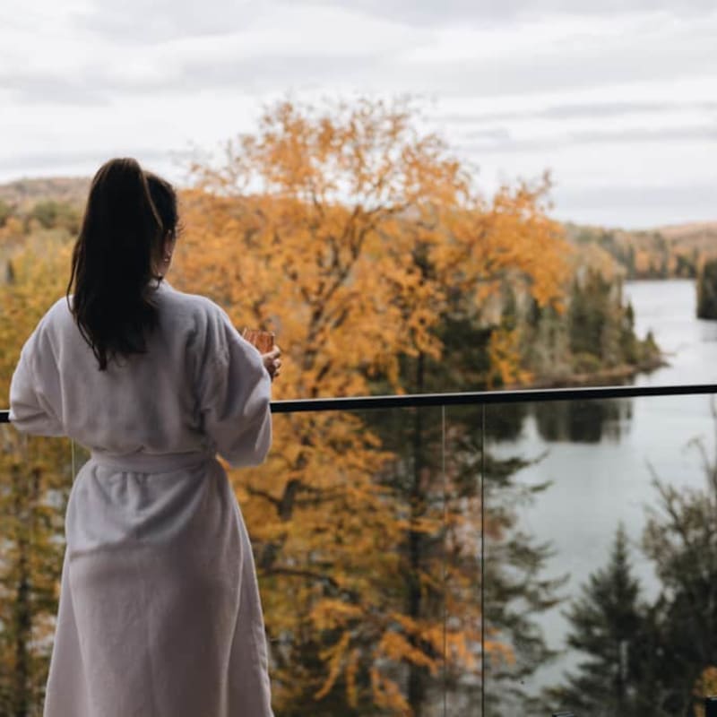 Femme en peignoir regardant un lac et paysage d'automne, Domaine des Constellations.