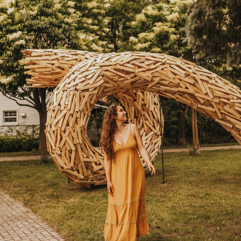 Femme devant une sculpture dans un parc. 