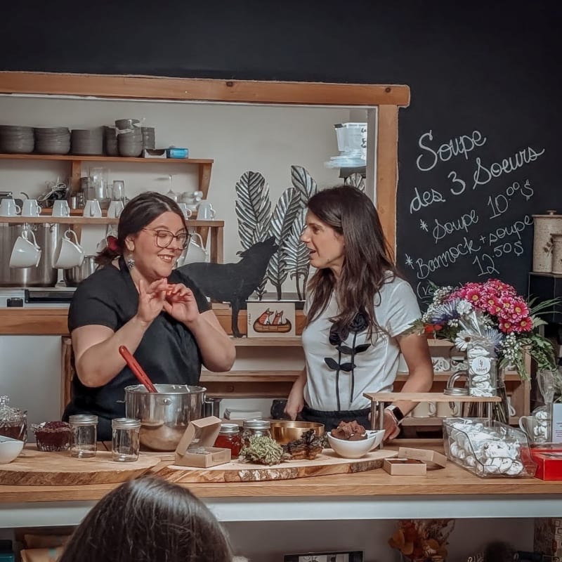 Two women standing behind a counter in a bakery.