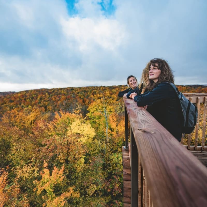 3 women hiking and admiring the fall view from a lookout at Parc des Montagnes Noires de Ripon.