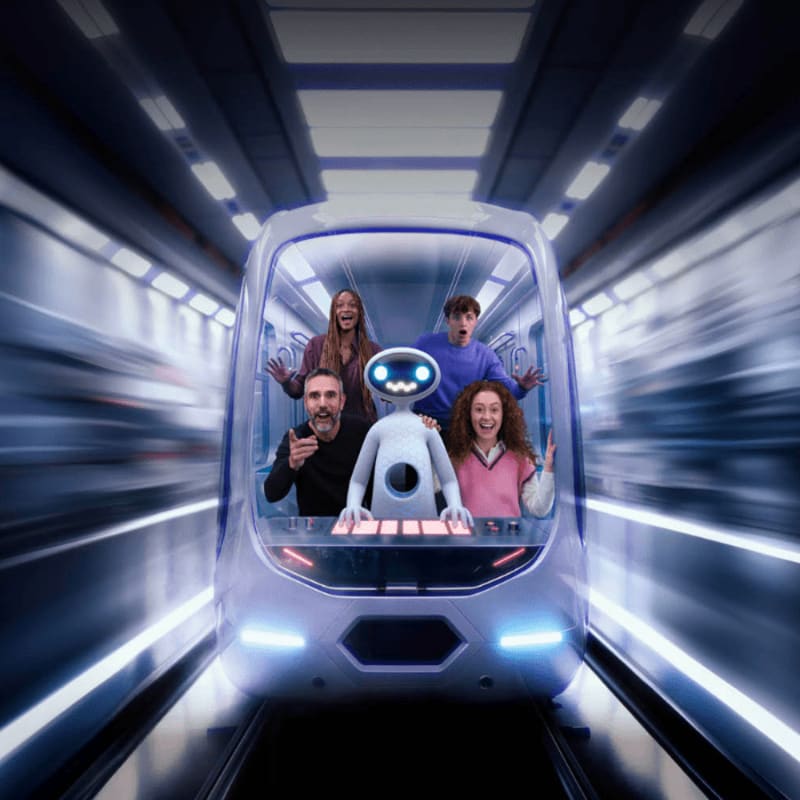 Devanture d'un wagon de métro futuriste qui file à toute allure dans un tunnel; le train est conduit par un robot animé entouré de 4 humains.