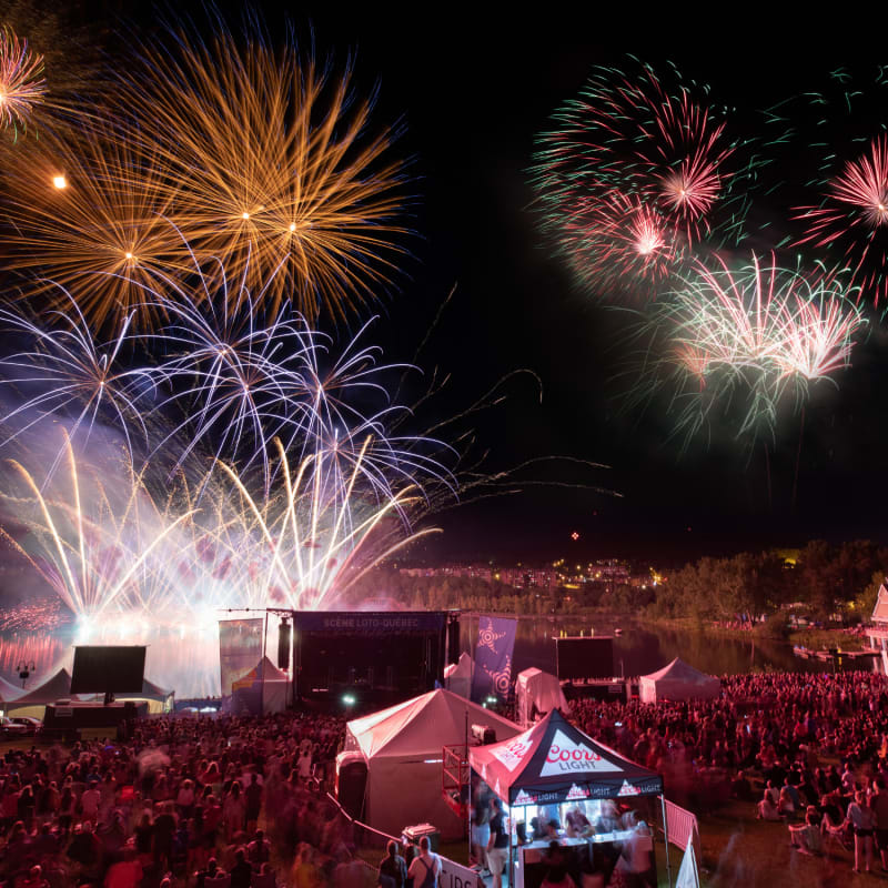 Feux d'artifice au-dessus d'une foule rassemblée lors de la Fête du Lac des Nations.